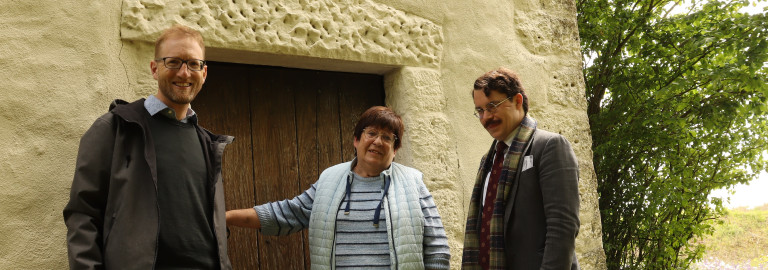 Dekan Max von Egidy gemeinsam mit Angelika Arlt und Pfarrer Marvin Askani vor der kleinsten Kirche im Dekanat Uffenheim. Sie ist wie alle 43 Kirchen am Tag der offenen Kirchen am Pfingstmontag, 25.5.26 geöffnet