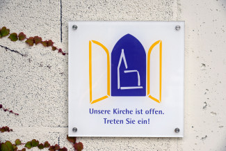 Schild offene Kirche lädt zum Eintreten und Verweilen ein. 